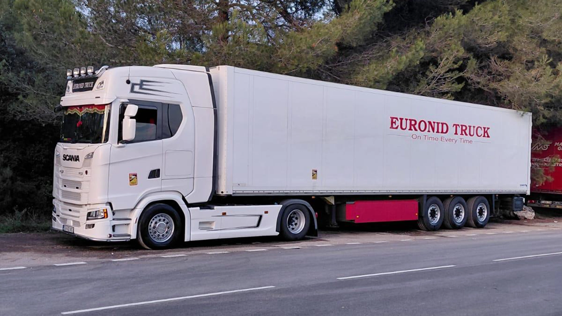 Ansamblu cap tractor Scania de culoare alba si semiremorca inscriptionata cu numele si sloganul firmei Euronid
